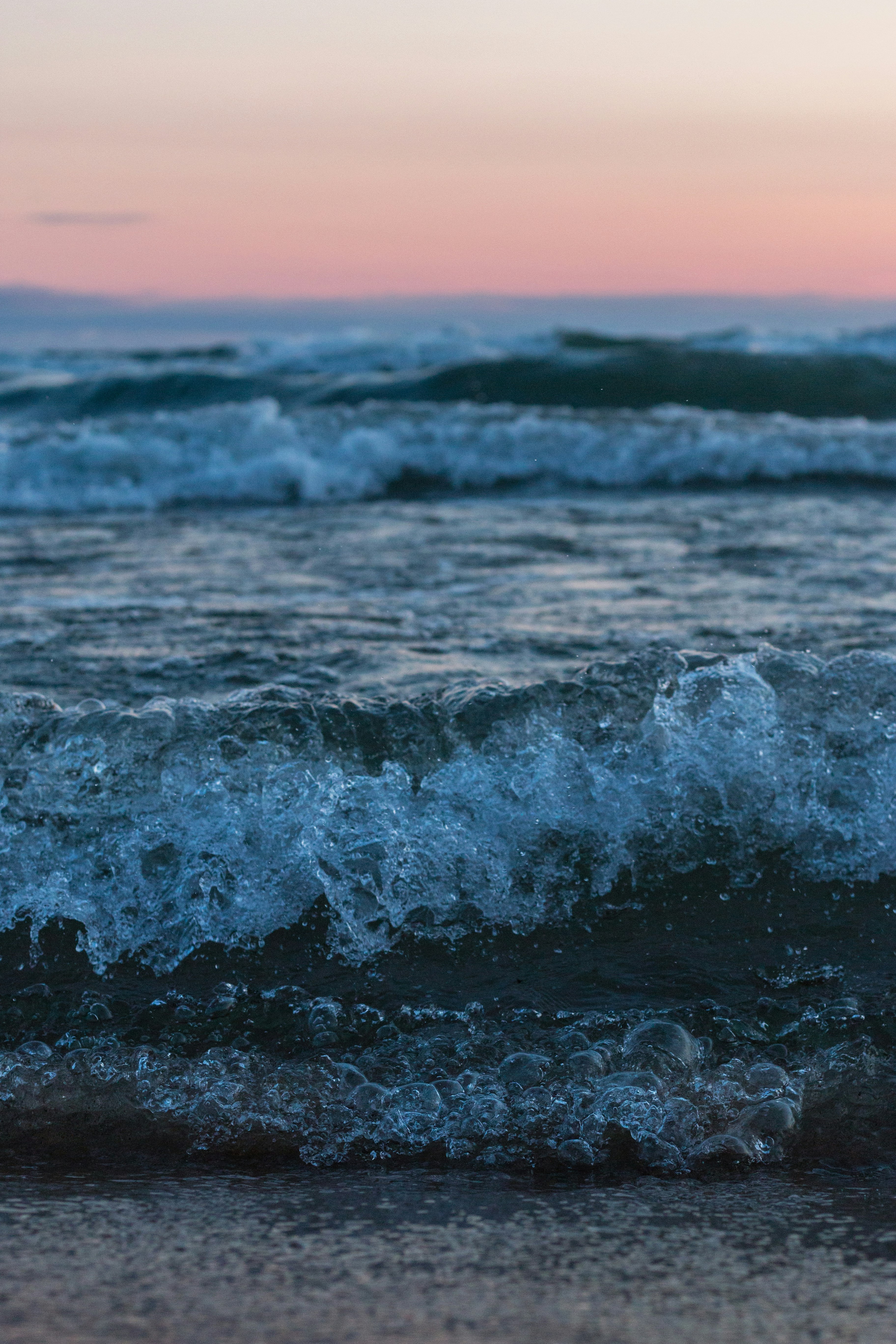 ocean waves crashing on shore during sunset